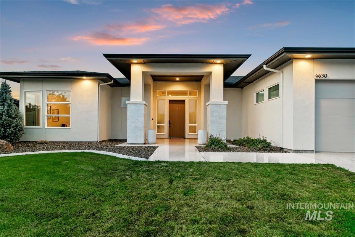 View of front of property featuring stucco siding, a front yard, and a garage