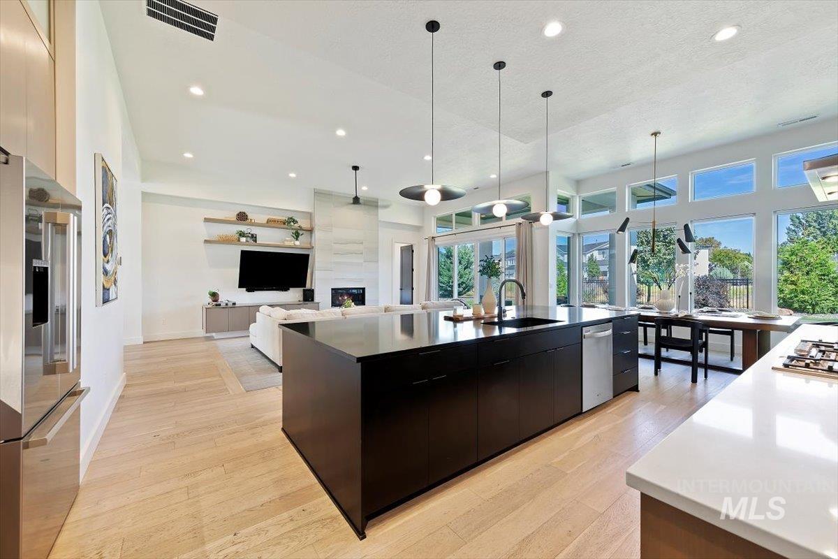 Kitchen featuring modern cabinets, open floor plan, light wood-type flooring, decorative light fixtures, and recessed lighting