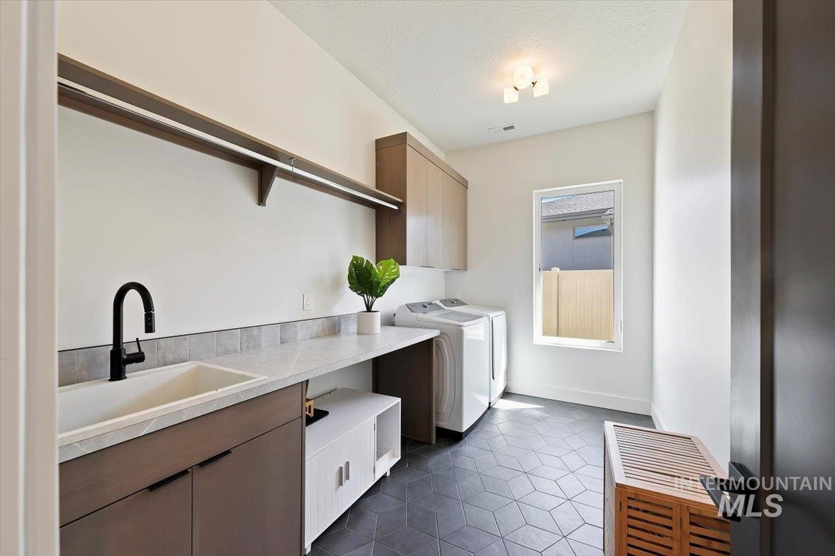 Laundry room featuring dark tile patterned floors, cabinet space, and separate washer and dryer