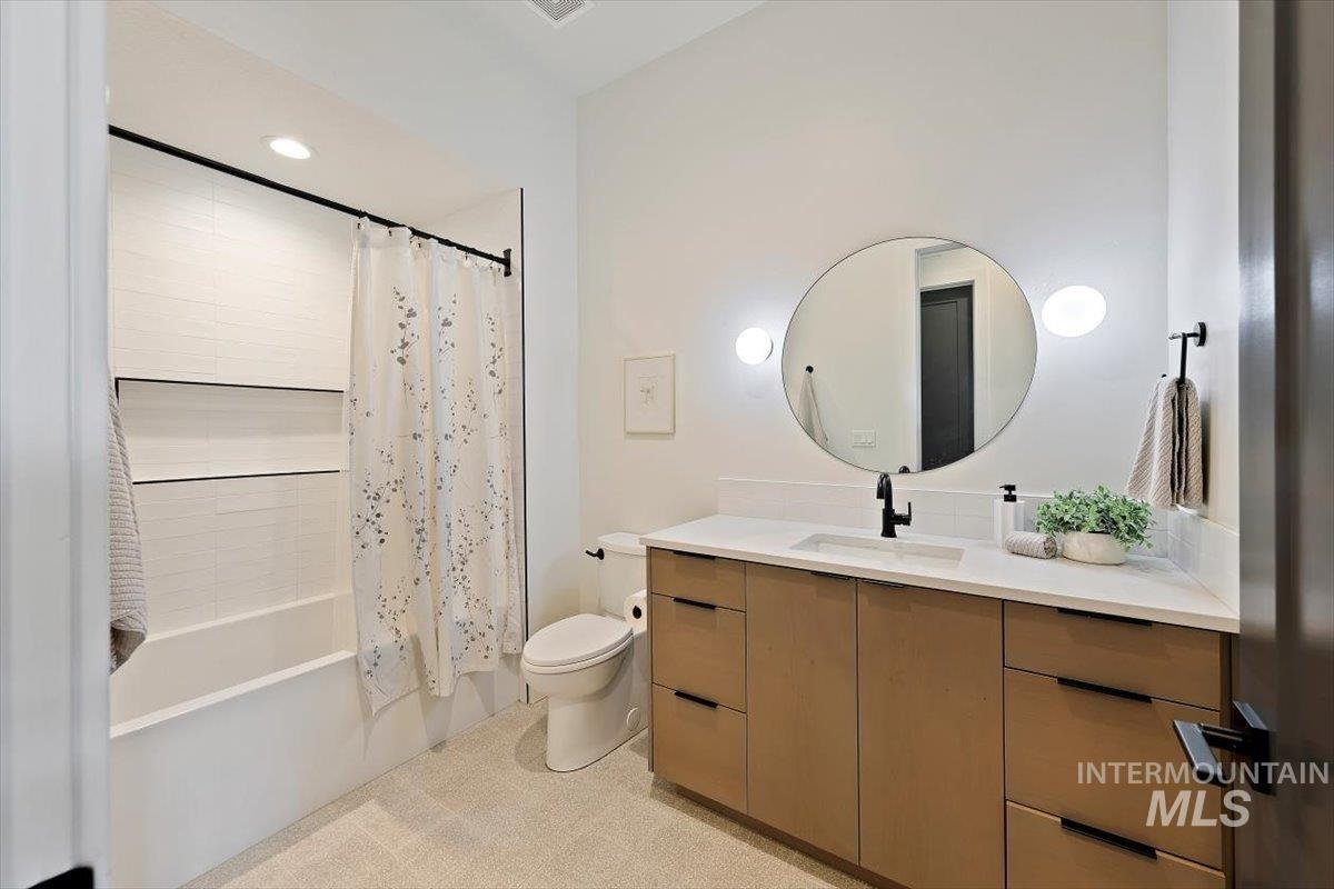 Bathroom with shower / bathtub combination with curtain, vanity, and recessed lighting