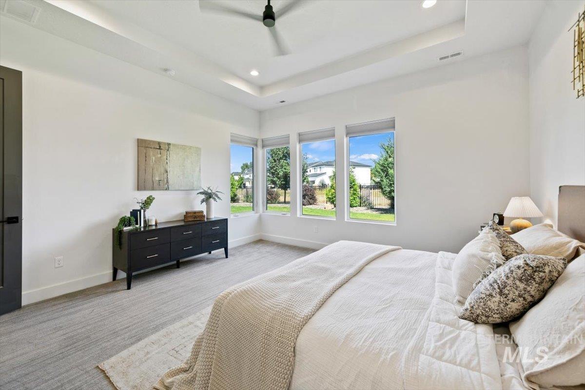 Carpeted bedroom with a tray ceiling, recessed lighting, and a ceiling fan