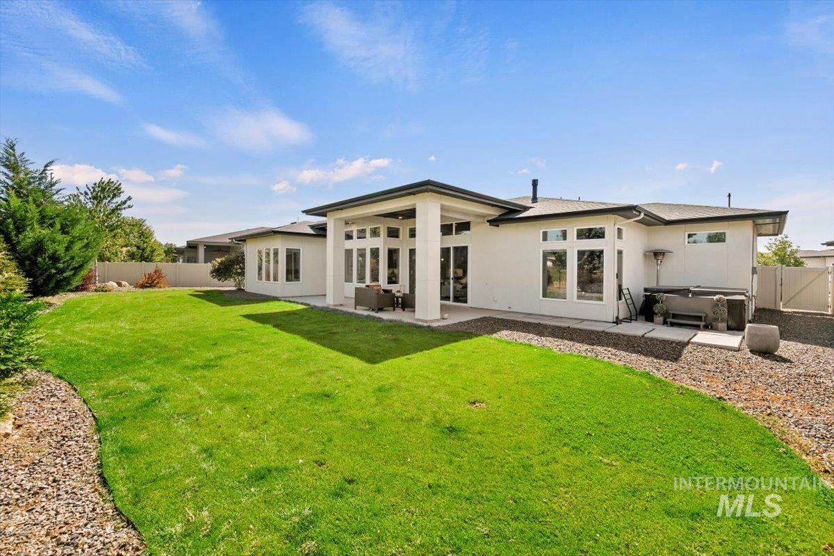 Rear view of house featuring a fenced backyard, a patio, a hot tub, and stucco siding