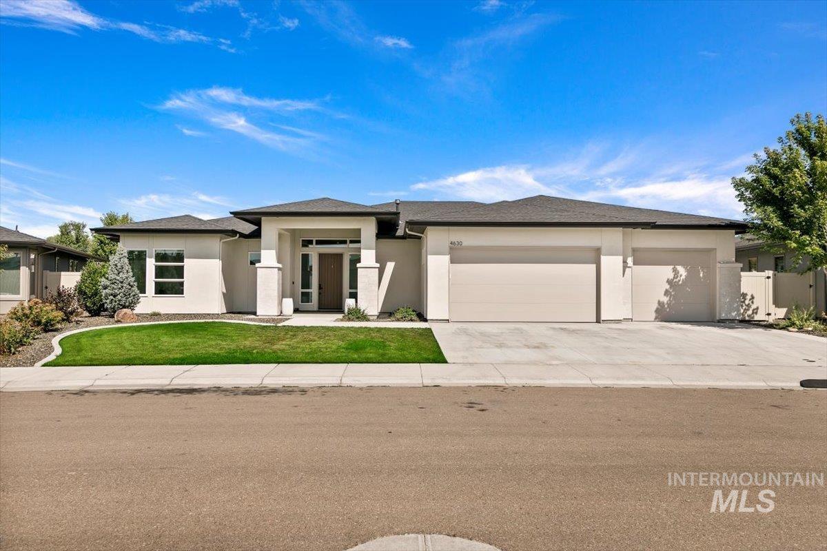 Prairie-style home with stucco siding, a garage, concrete driveway, a front yard, and a shingled roof
