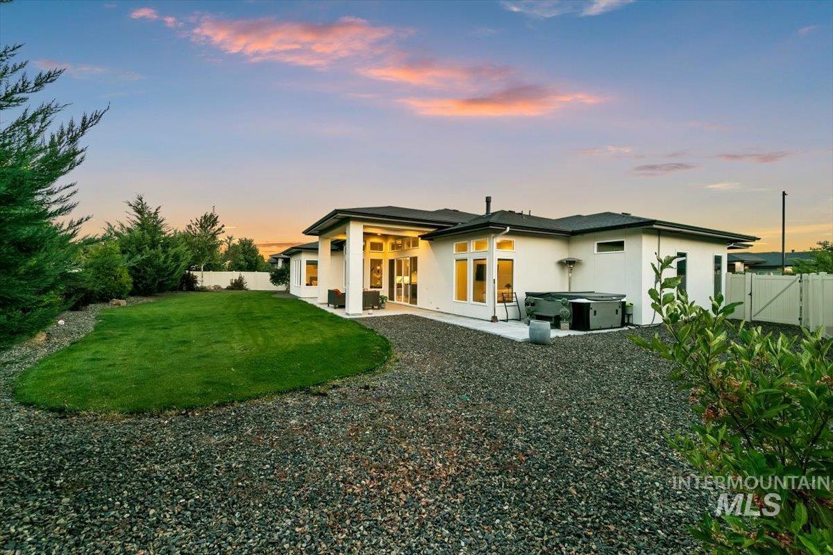 Back of house at dusk with a hot tub, stucco siding, a patio, and a fenced backyard