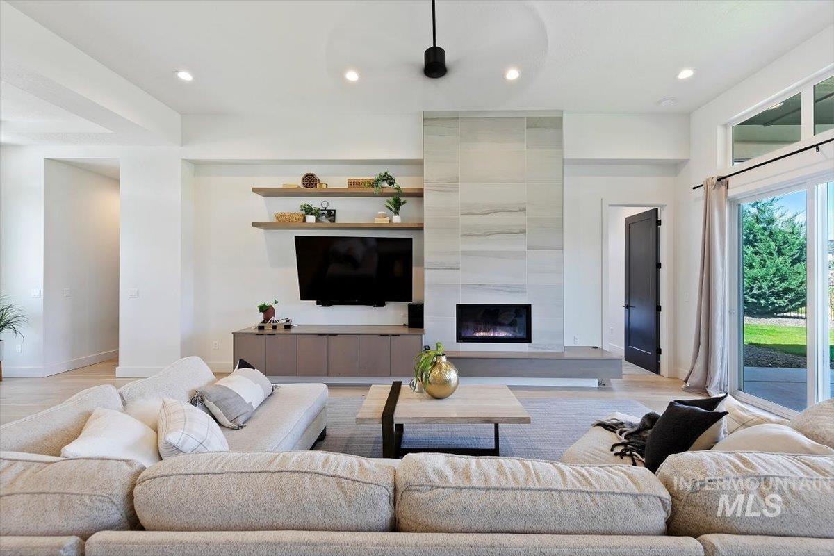 Living room featuring recessed lighting, light wood-style floors, a fireplace, and ceiling fan