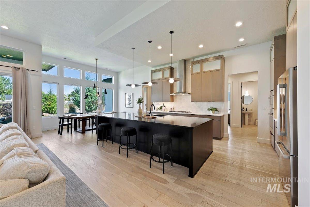 Kitchen featuring open floor plan, hanging light fixtures, decorative backsplash, a kitchen bar, and a spacious island