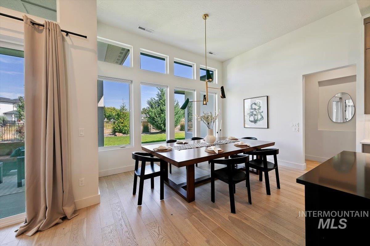 Dining space featuring light wood finished floors and a towering ceiling