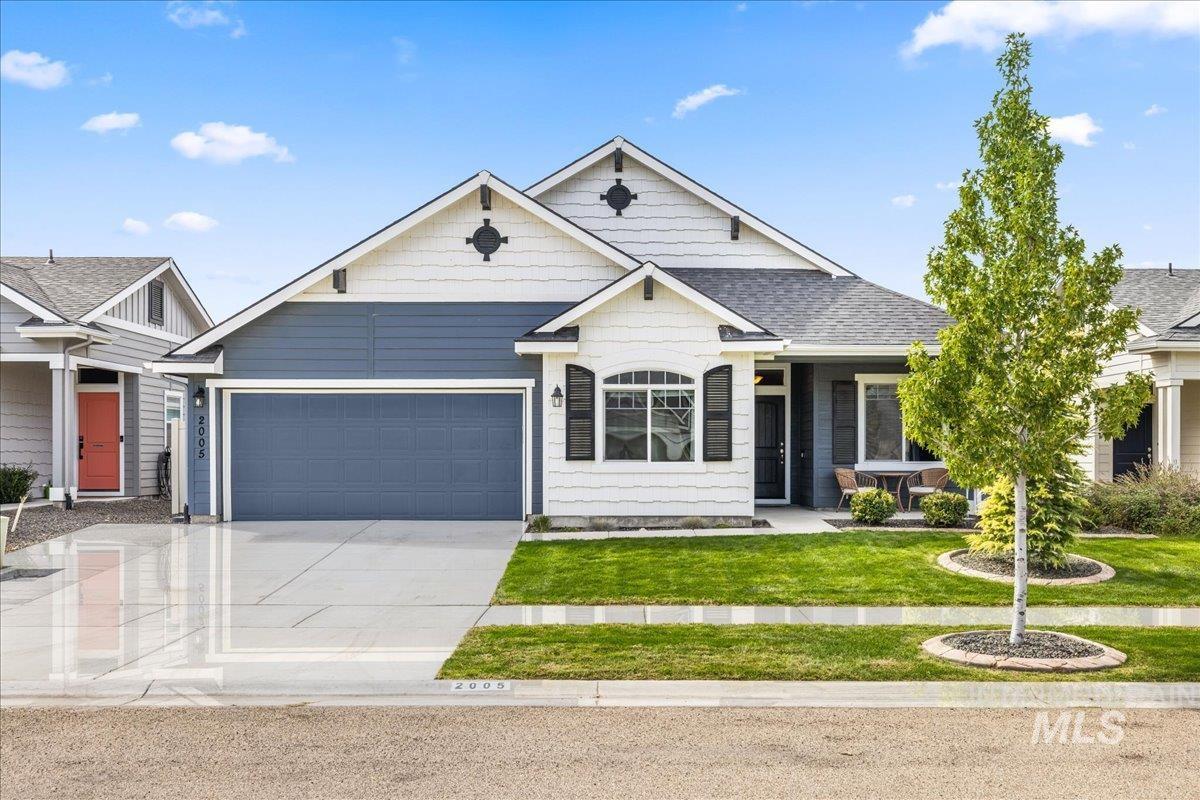Craftsman house with driveway, a front yard, an attached garage, and roof with shingles