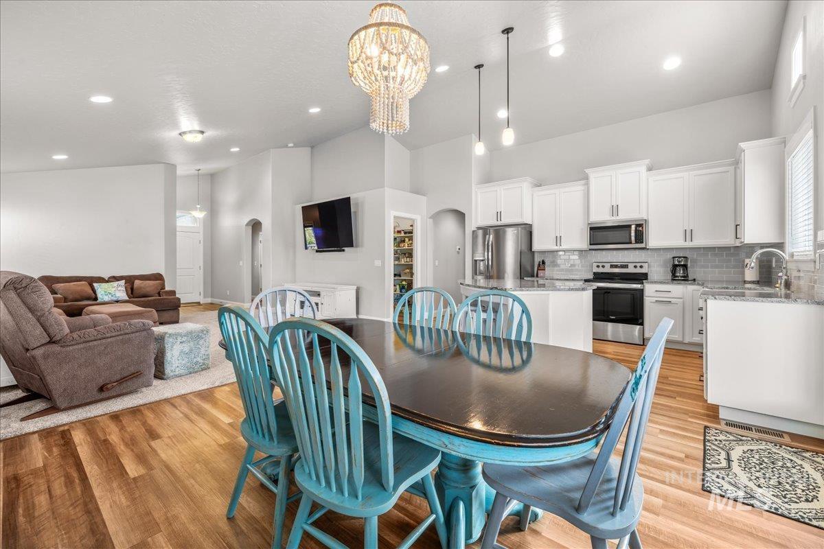 Dining space featuring arched walkways, recessed lighting, a chandelier, and light wood finished floors