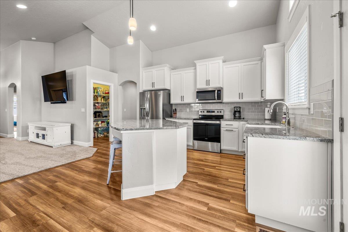 Kitchen with arched walkways, a breakfast bar area, open floor plan, appliances with stainless steel finishes, and recessed lighting