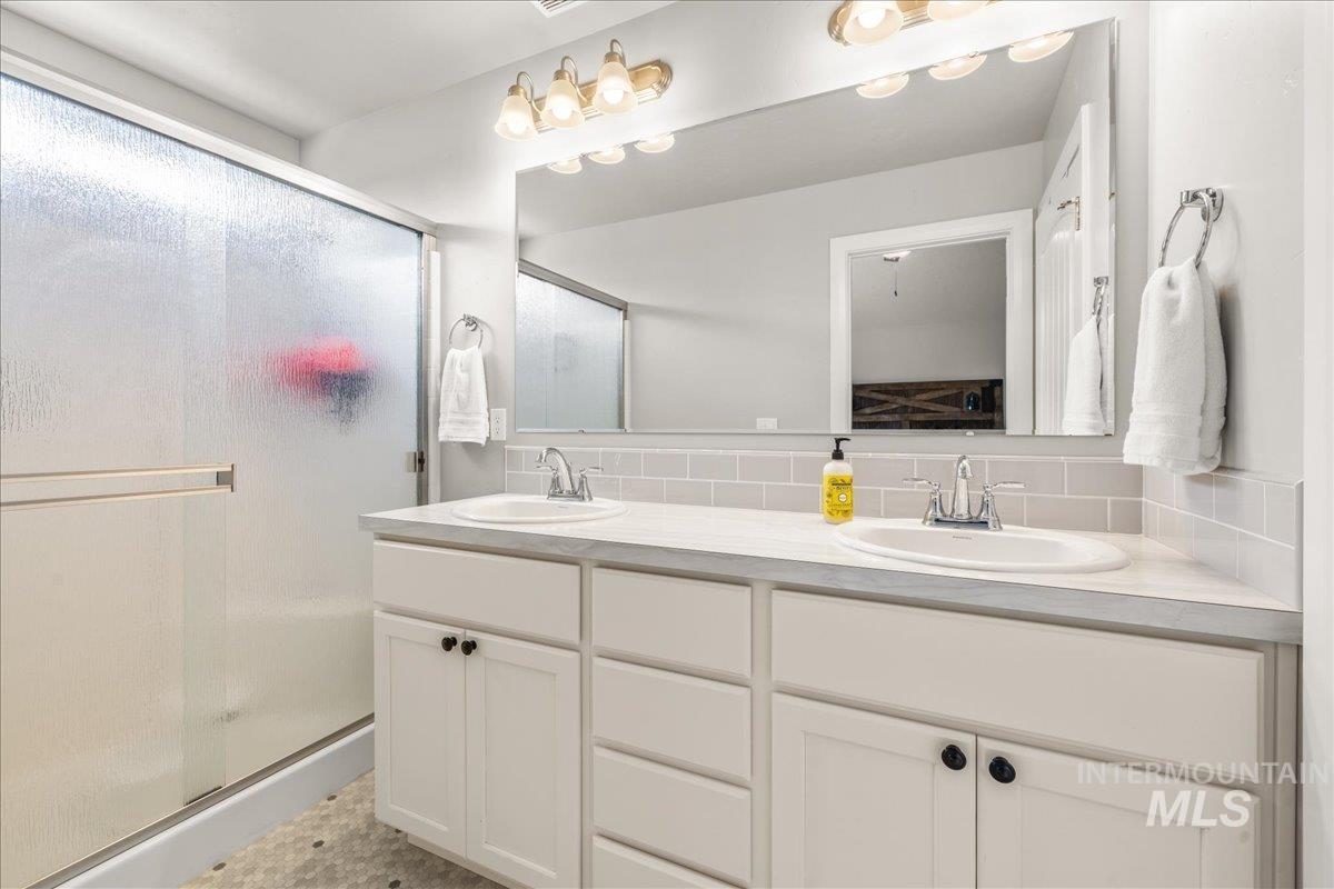 Bathroom with a stall shower, double vanity, and decorative backsplash