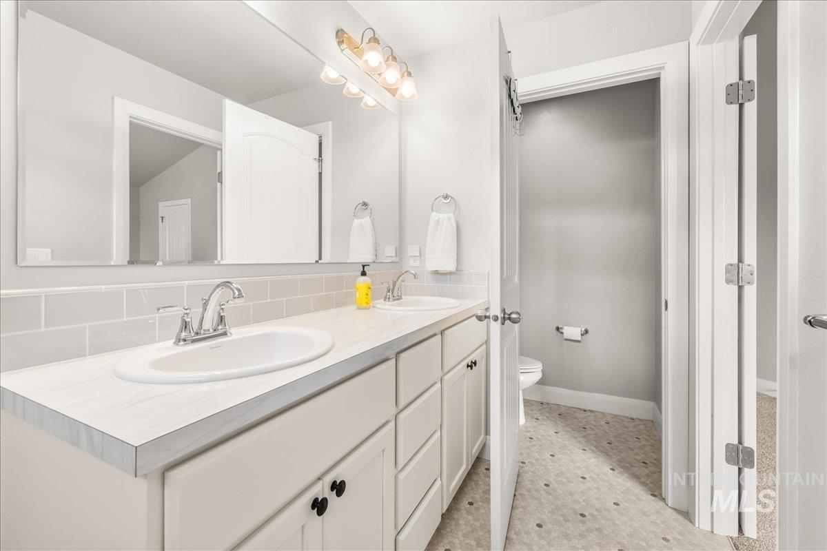Full bath with double vanity and decorative backsplash