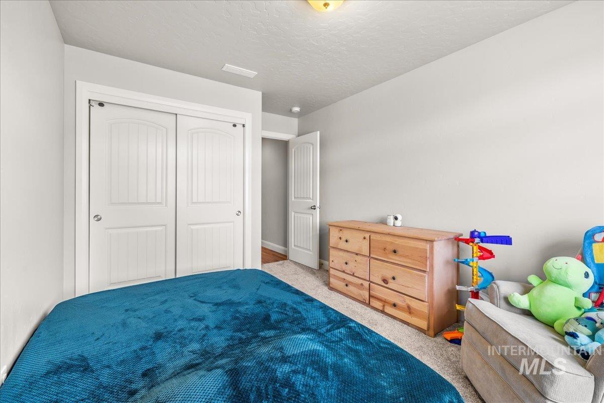Bedroom with carpet flooring, a textured ceiling, and a closet
