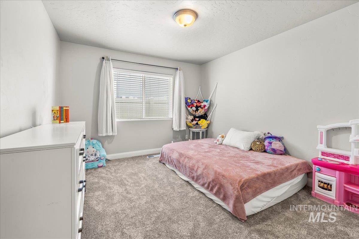 Bedroom with light colored carpet and a textured ceiling