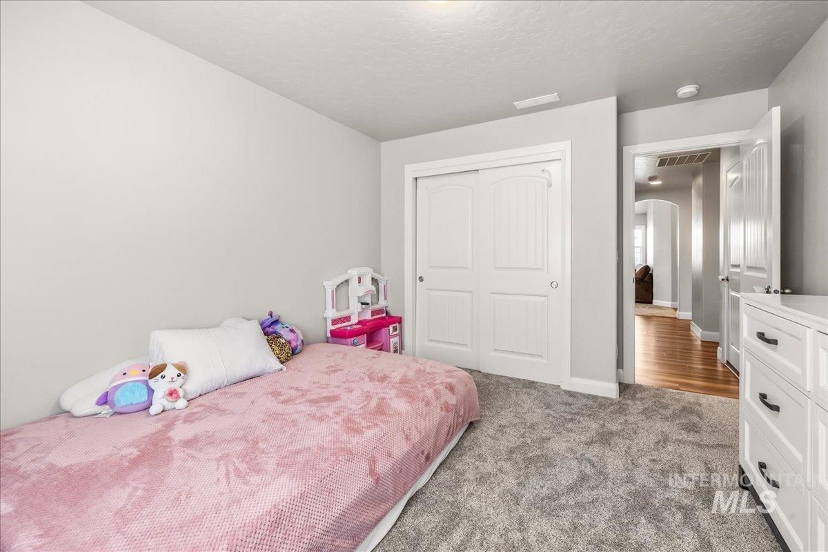 Bedroom featuring light carpet, a closet, arched walkways, and a textured ceiling
