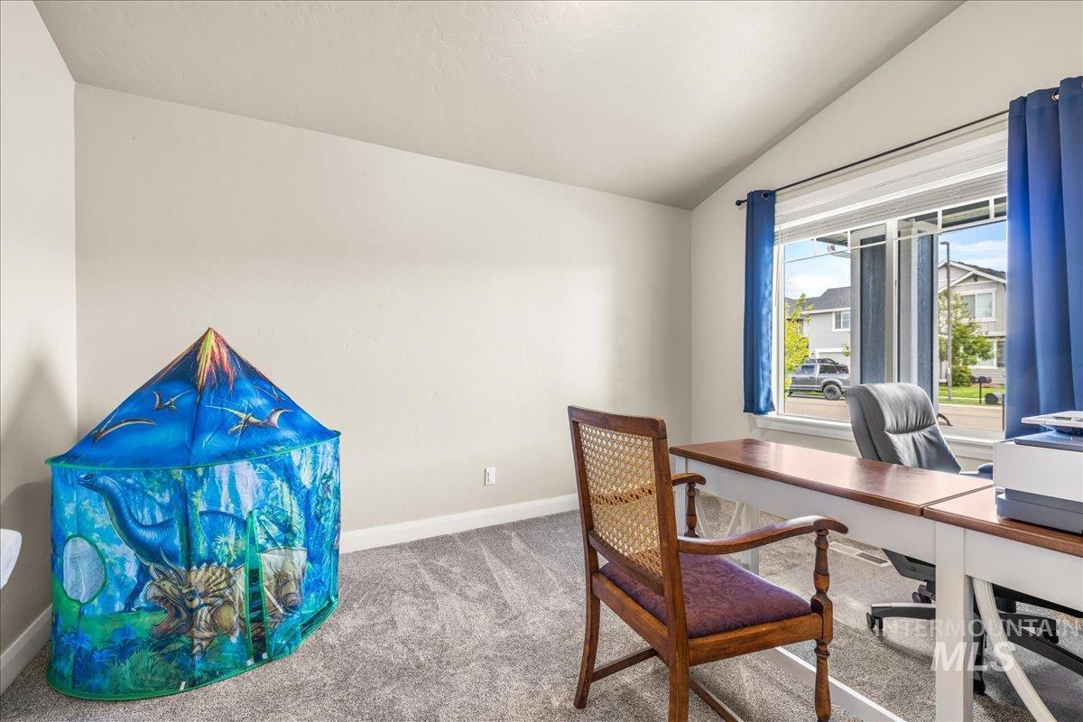 Carpeted office with vaulted ceiling and baseboards