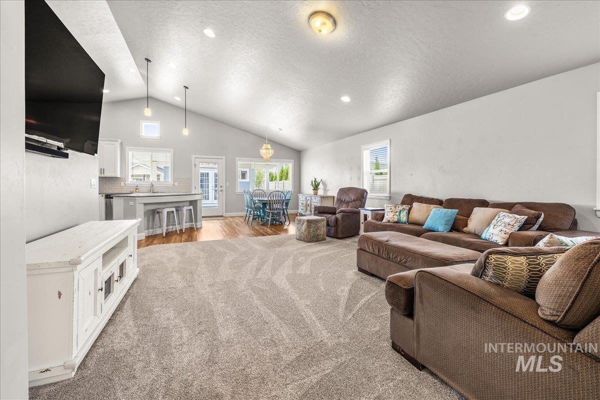 Living area with a textured ceiling, light wood-style flooring, recessed lighting, and high vaulted ceiling