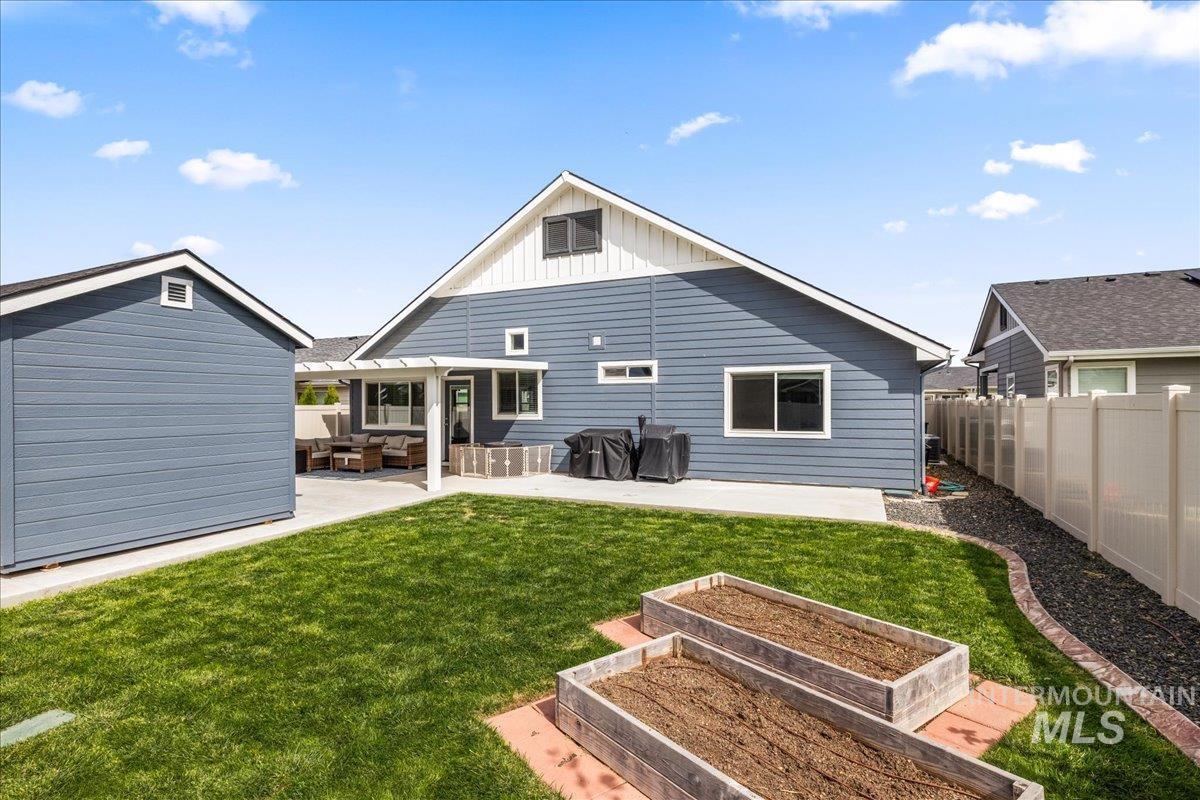 Back of property featuring a patio, board and batten siding, a vegetable garden, and a fenced backyard