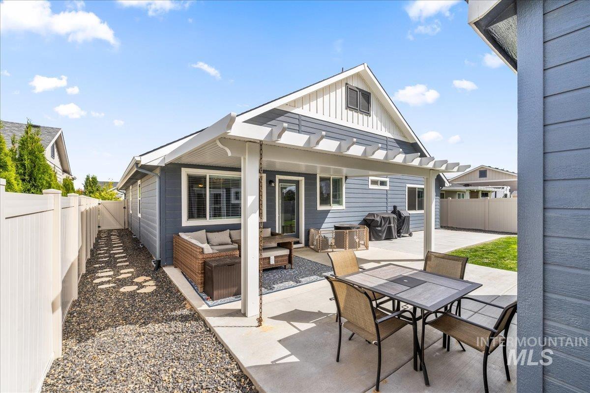 Rear view of house featuring a fenced backyard, board and batten siding, a patio, and an outdoor living space