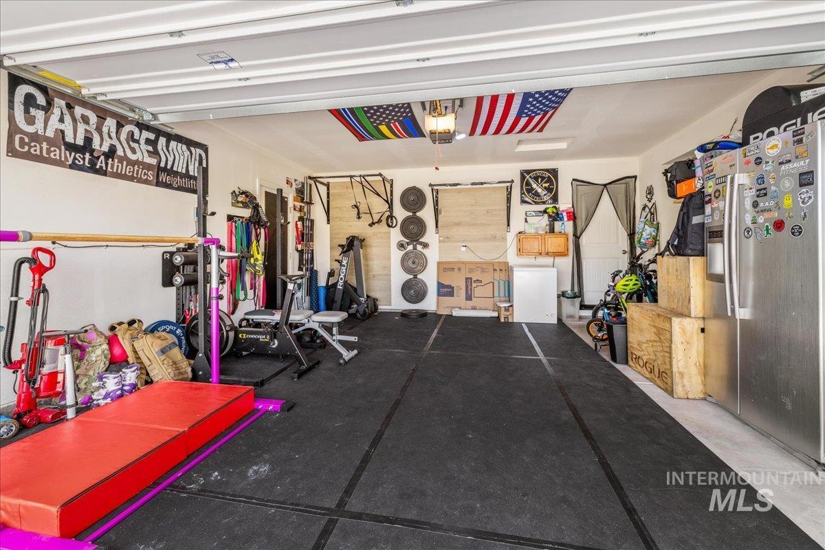 Garage featuring stainless steel fridge with ice dispenser and a garage door opener