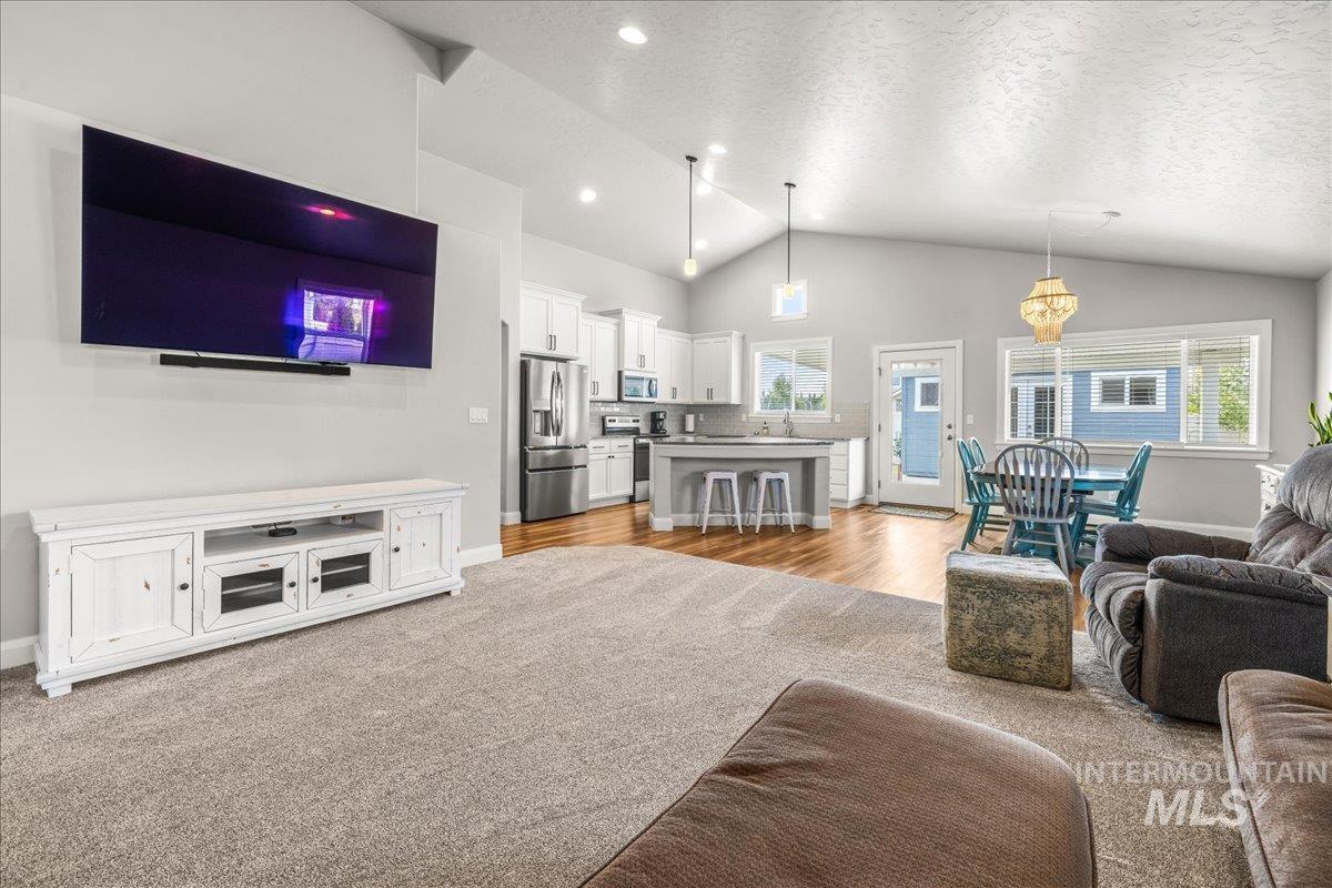 Living area featuring healthy amount of natural light, a textured ceiling, high vaulted ceiling, and light wood-style floors