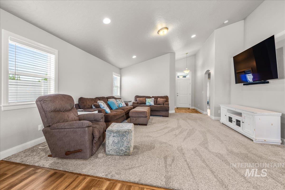 Living area featuring recessed lighting, lofted ceiling, light wood finished floors, arched walkways, and a textured ceiling