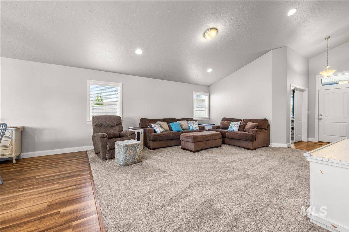 Living room with a textured ceiling, plenty of natural light, light wood finished floors, recessed lighting, and high vaulted ceiling