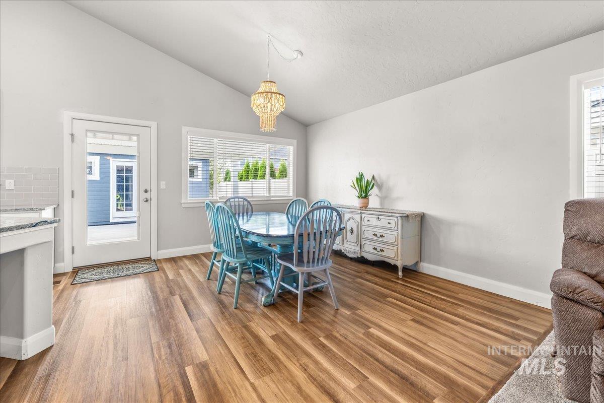 Dining room featuring lofted ceiling, plenty of natural light, light wood-type flooring, and a chandelier