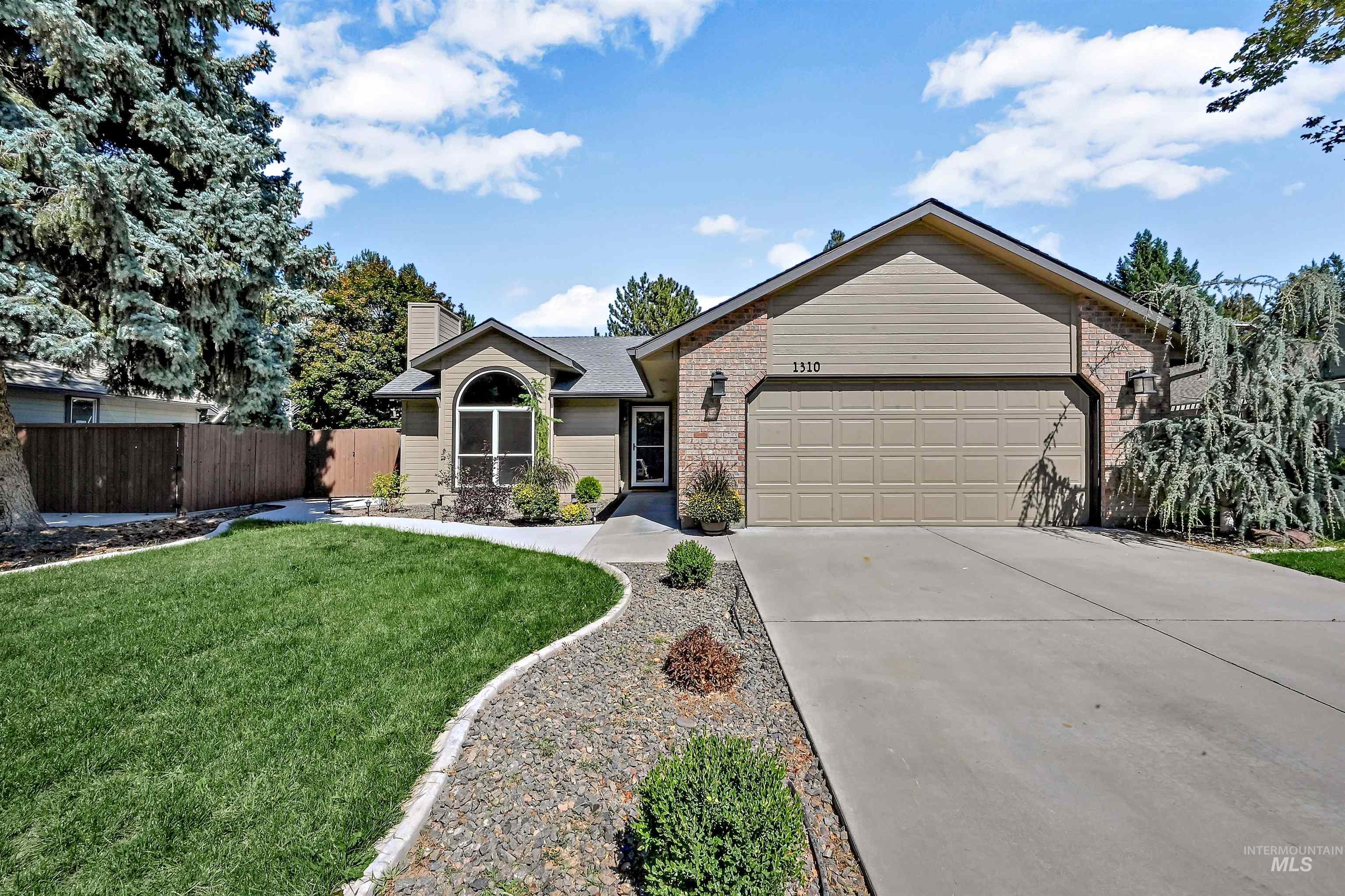 Ranch-style home featuring concrete driveway, a chimney, brick siding, and an attached garage