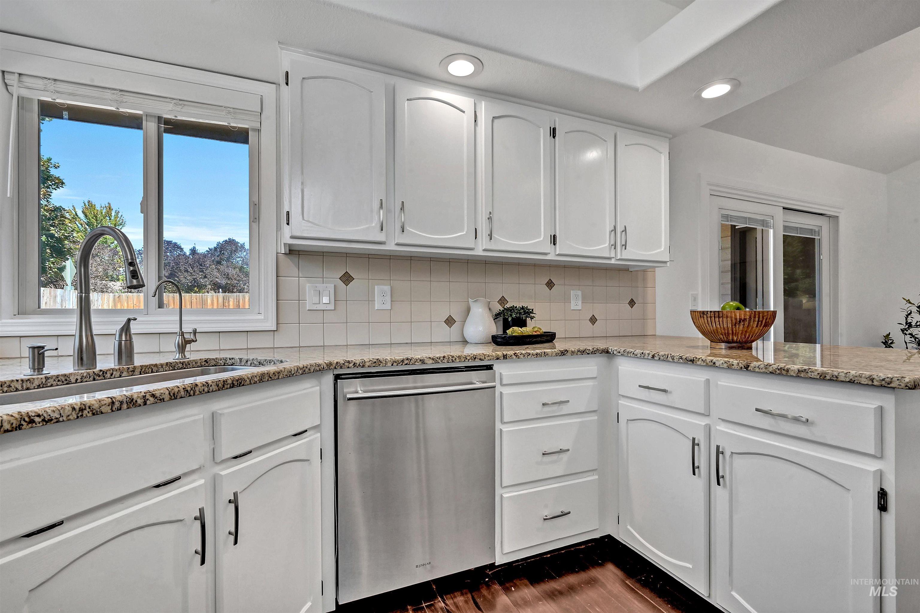 Kitchen featuring white cabinetry, stainless steel dishwasher, decorative backsplash, and recessed lighting