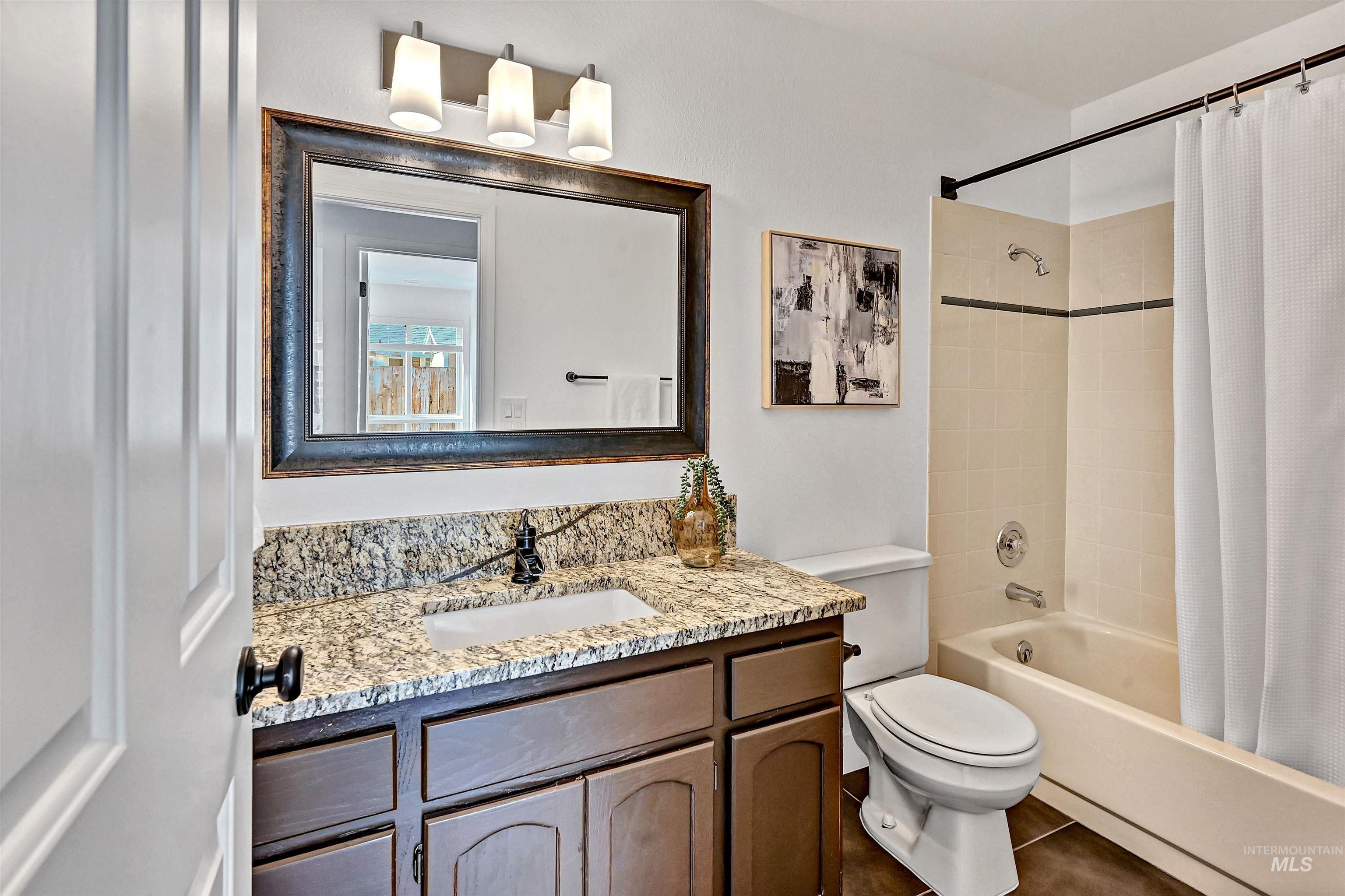 Bathroom with shower / tub combo, vanity, and dark tile patterned flooring