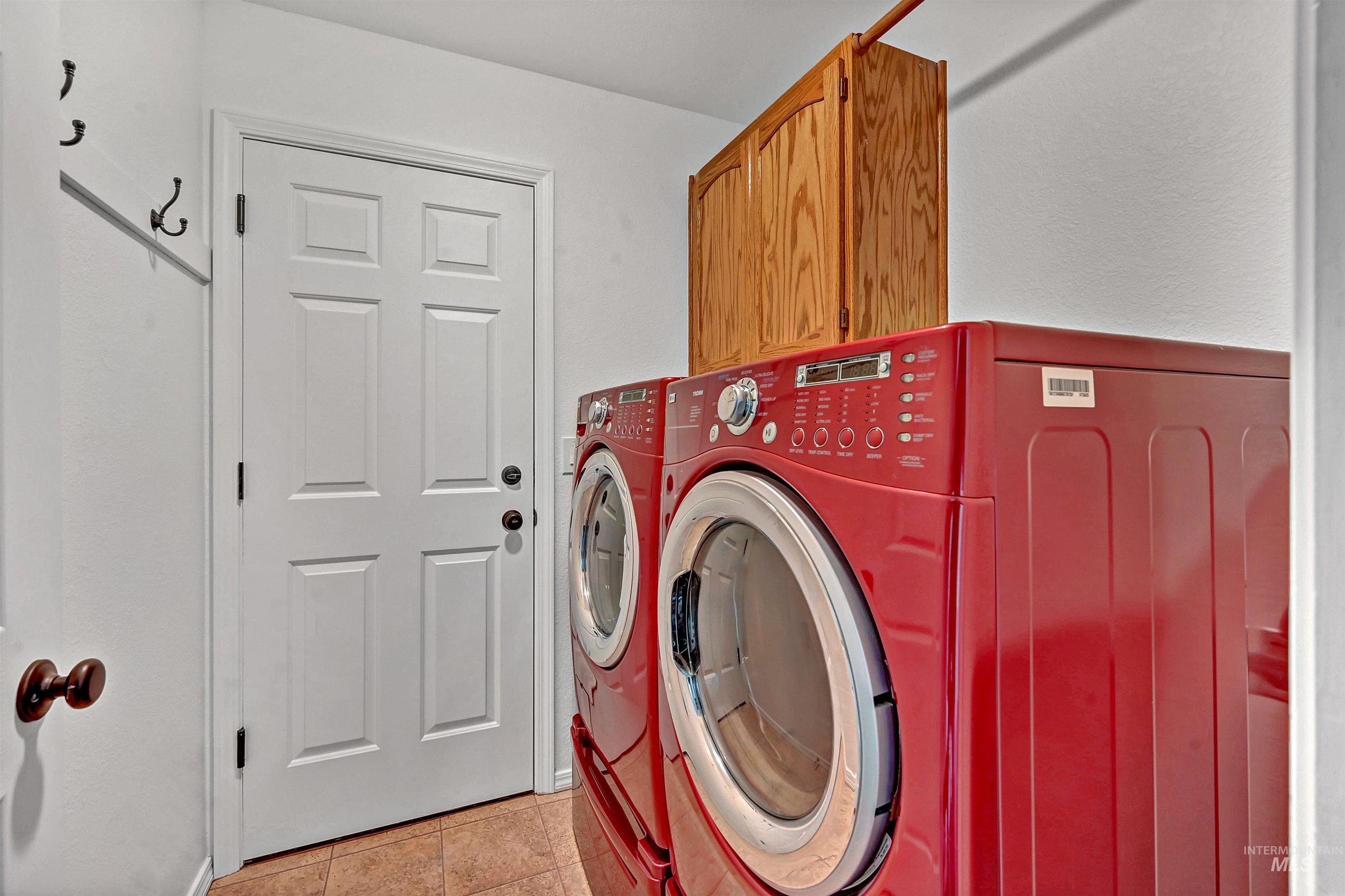 Laundry room with light tile patterned floors, washing machine and dryer, and cabinet space
