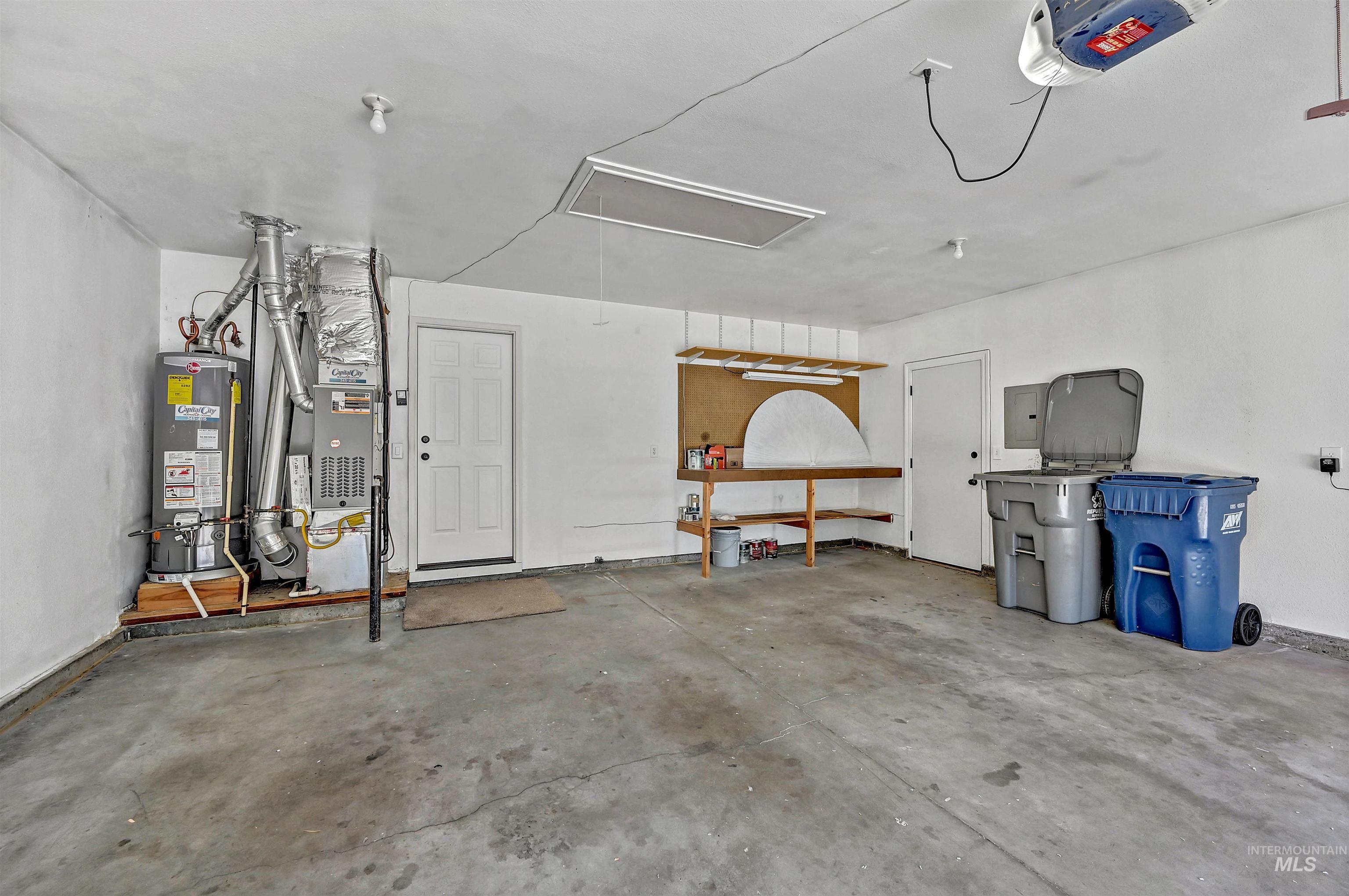 Garage featuring a garage door opener, water heater, and electric panel