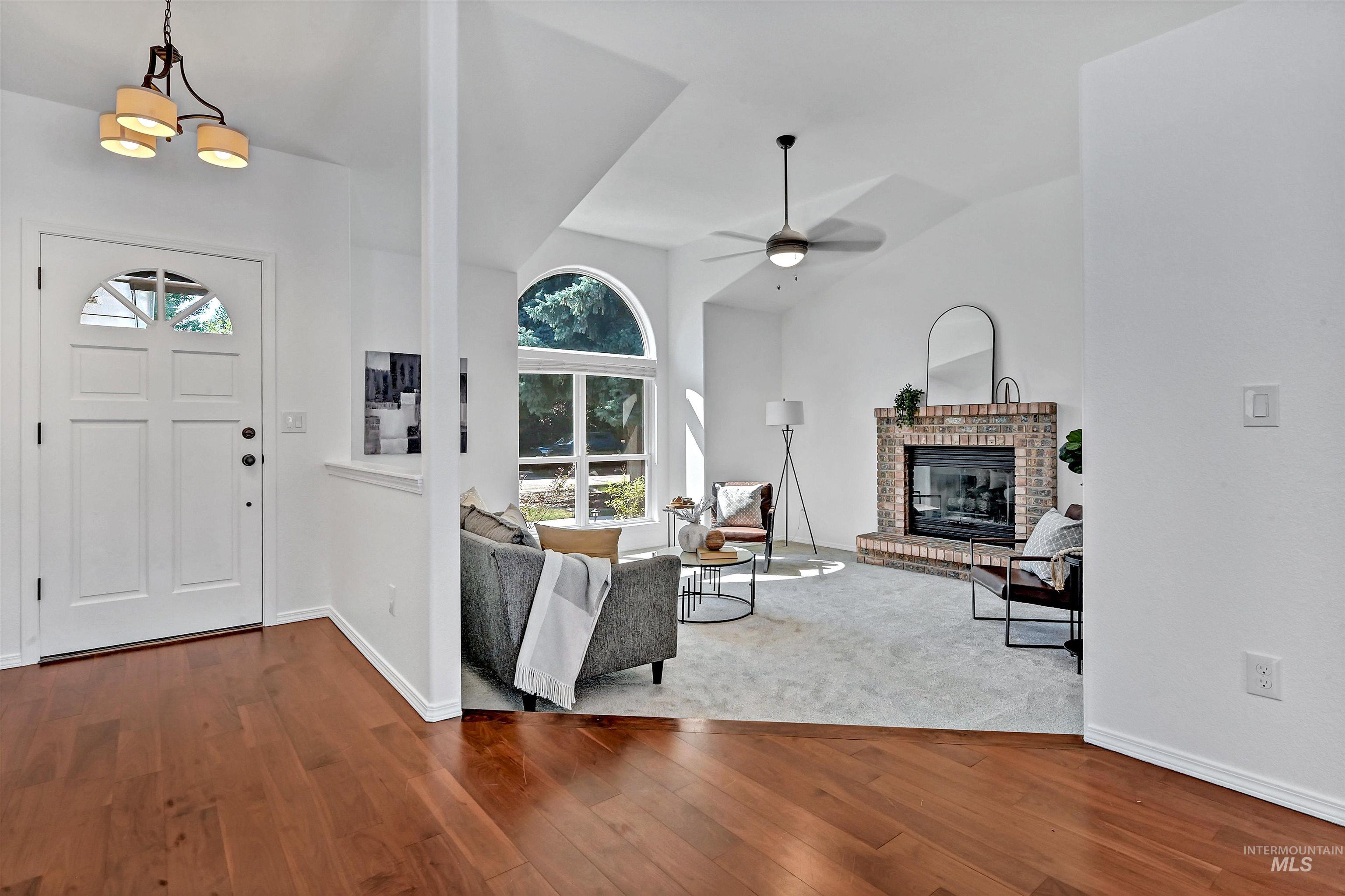 Entryway with dark wood-style floors, a brick fireplace, lofted ceiling, and a ceiling fan