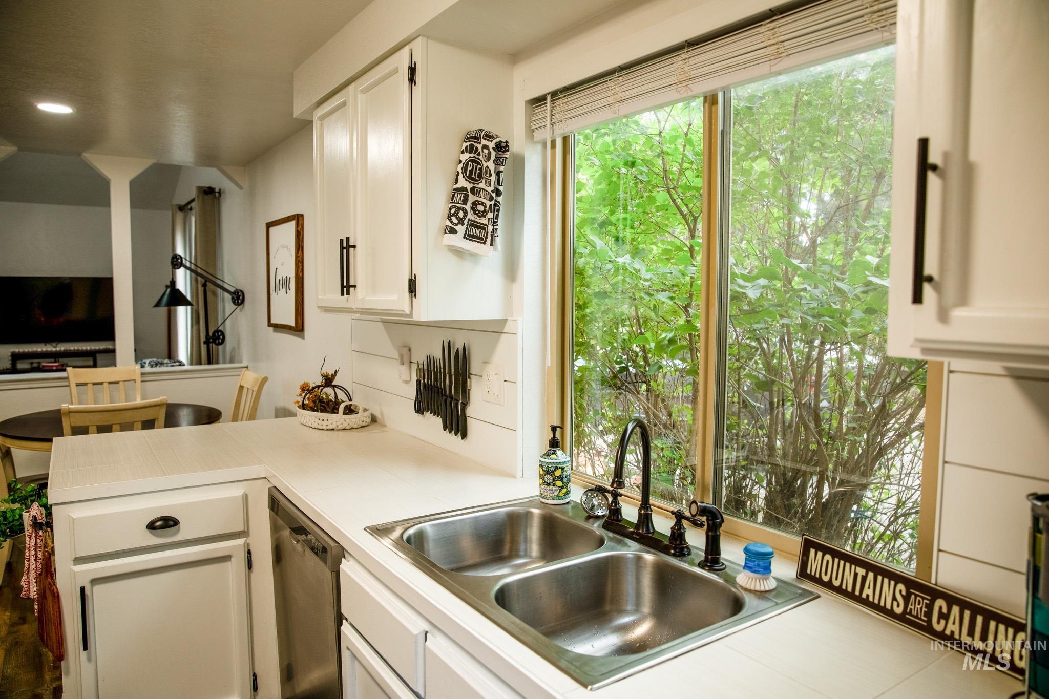 Kitchen with white cabinets, light countertops, a peninsula, stainless steel dishwasher, and recessed lighting
