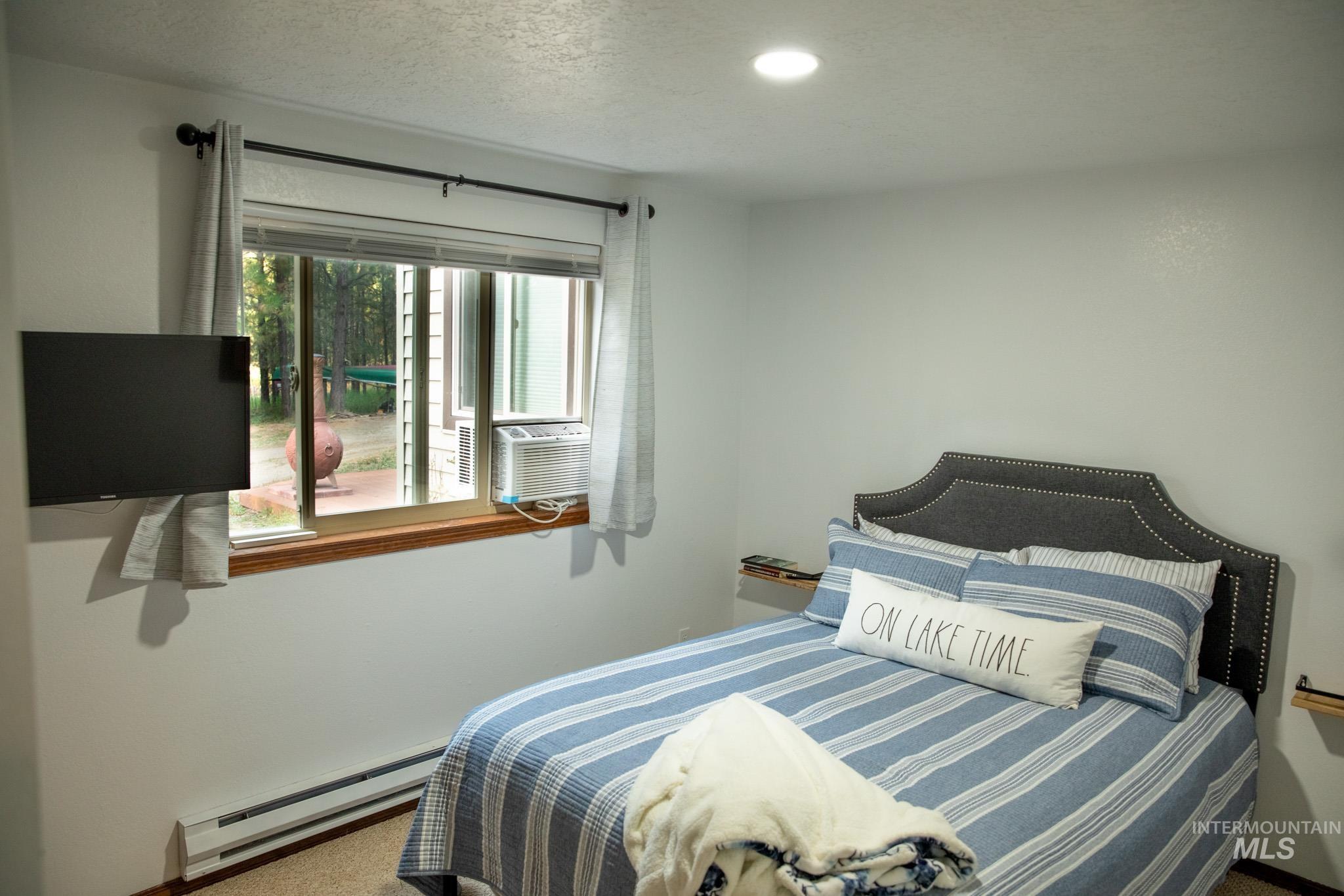 Bedroom with baseboard heating, carpet flooring, a textured ceiling, and cooling unit