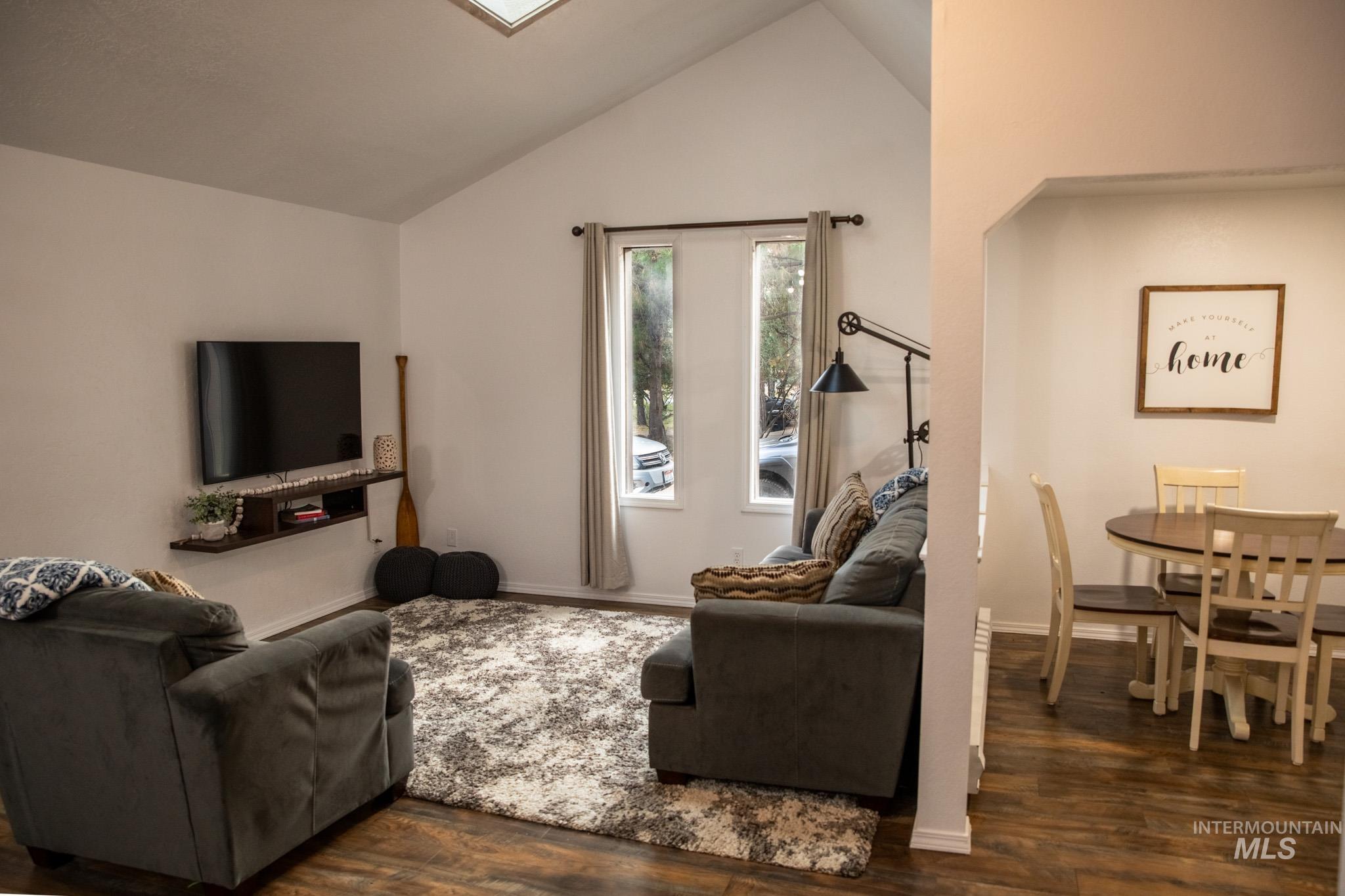 Living area featuring dark wood-style flooring and lofted ceiling