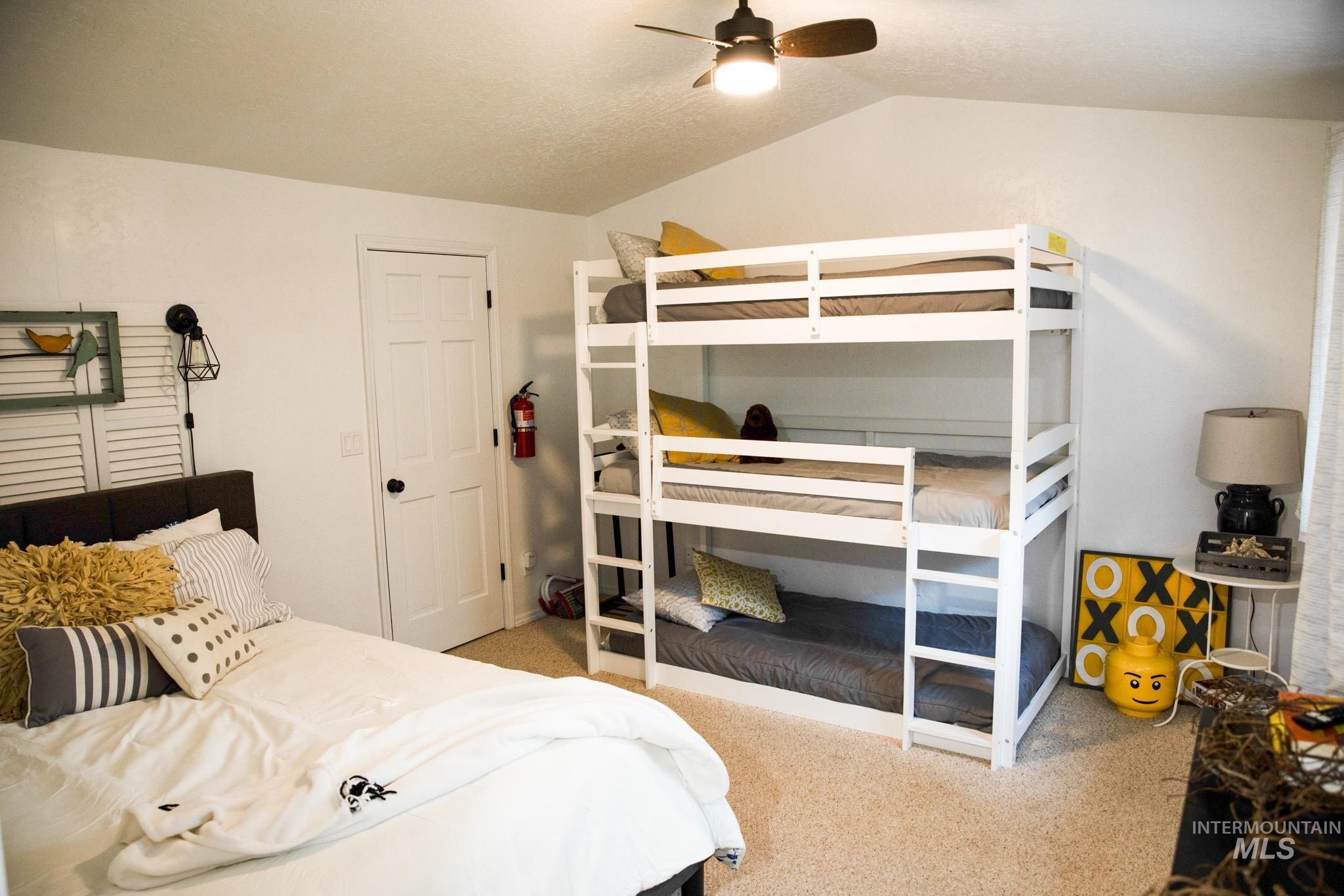 Bedroom featuring light carpet, lofted ceiling, and a ceiling fan