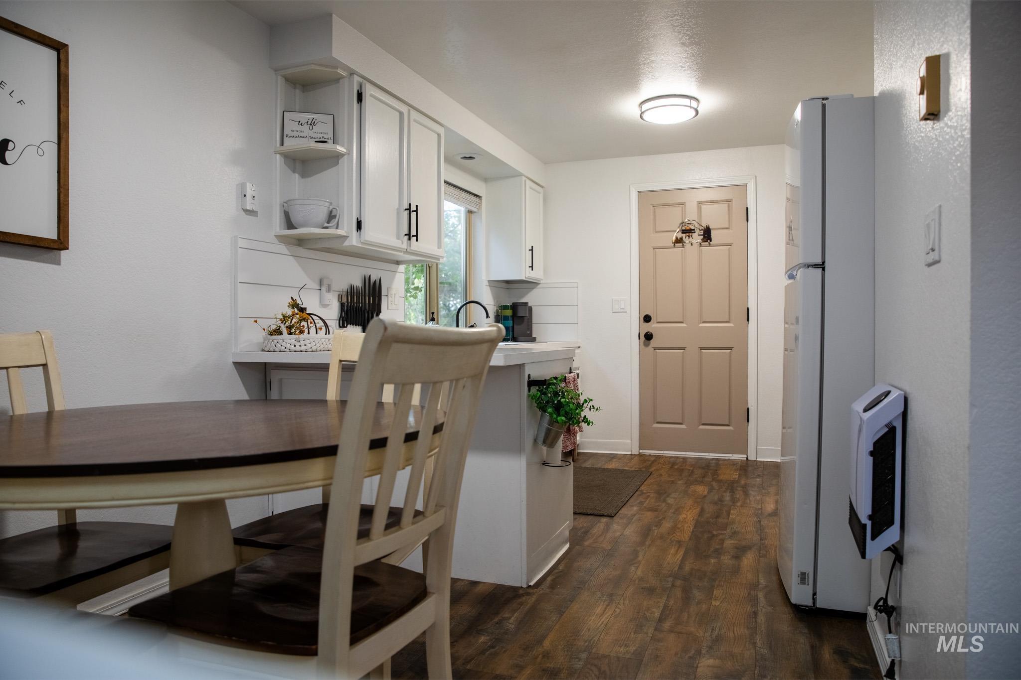 Kitchen featuring white cabinetry, open shelves, dark wood-style floors, freestanding refrigerator, and light countertops