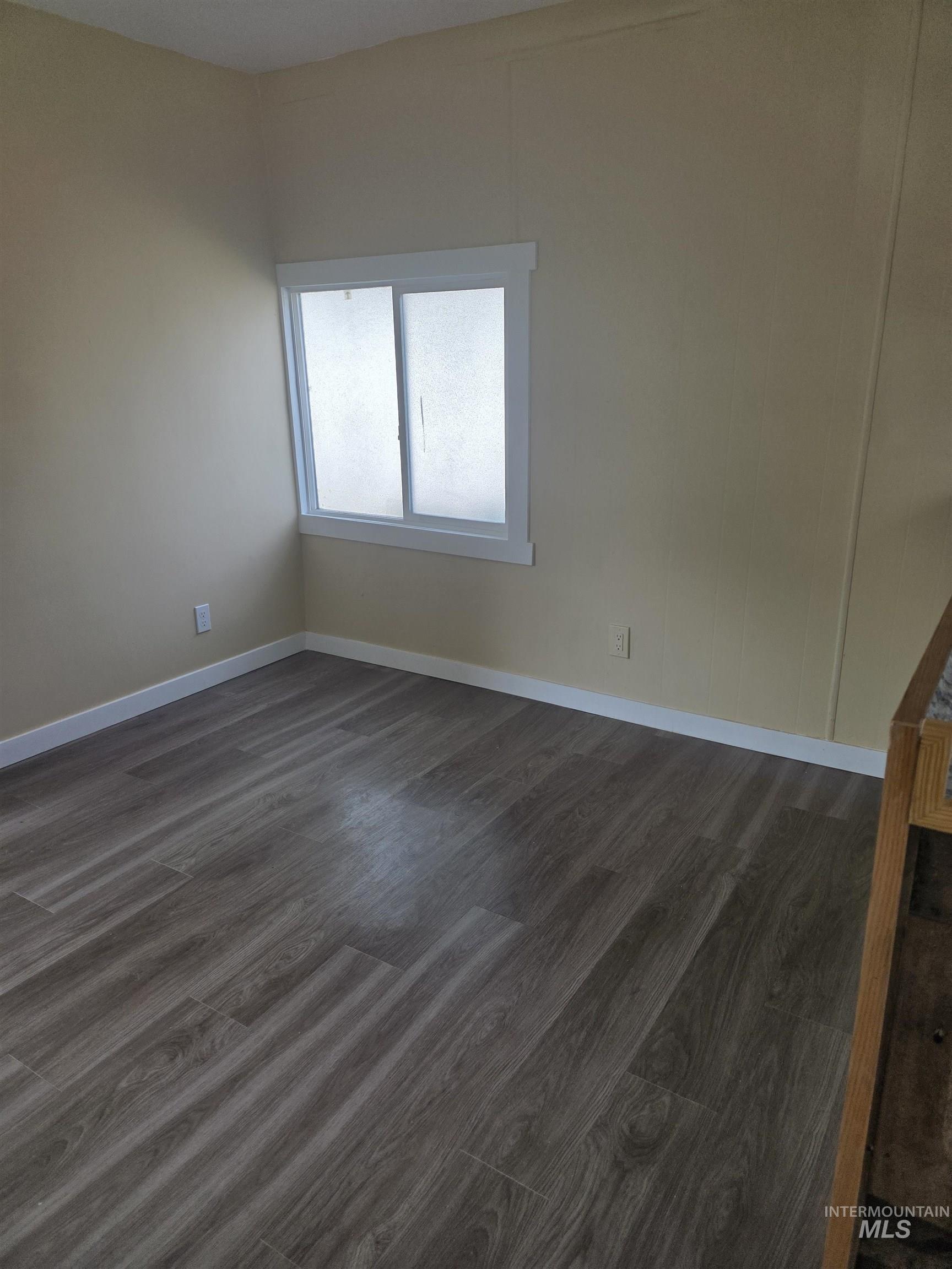 Unfurnished room with dark wood finished floors and baseboards