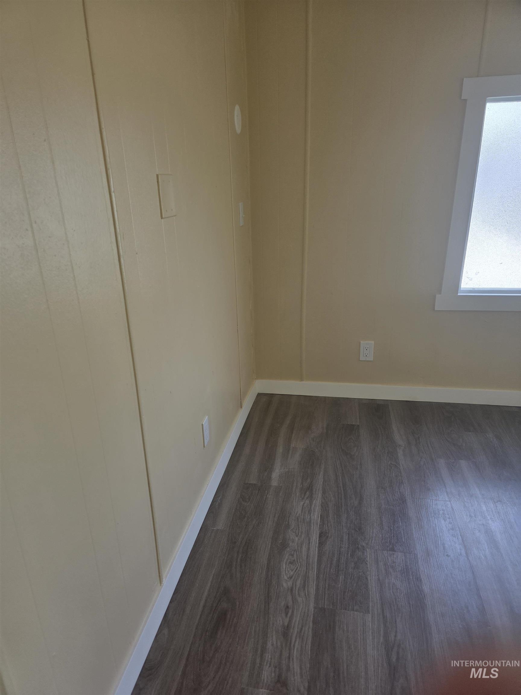 Empty room featuring dark wood finished floors and baseboards