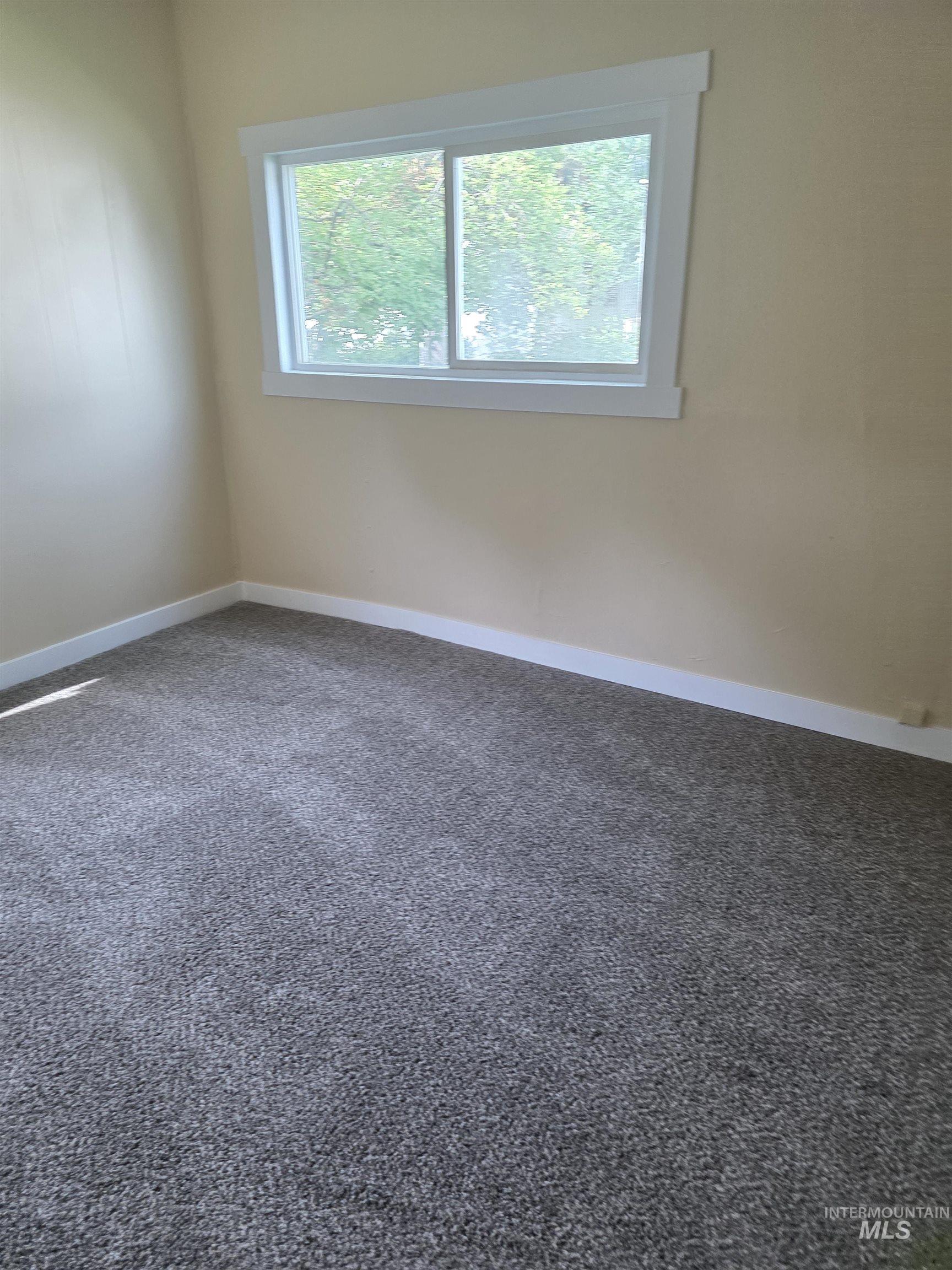 Spare room with dark colored carpet and baseboards
