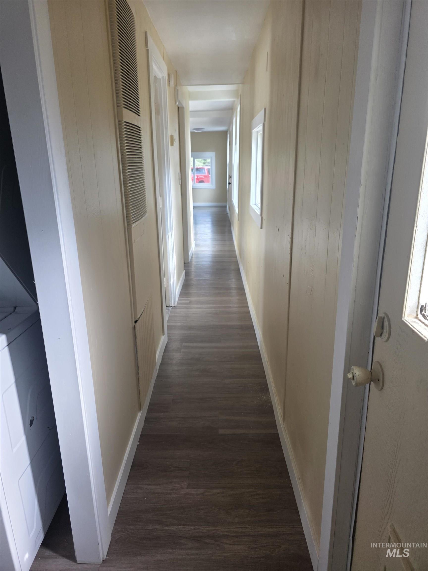 Corridor featuring dark wood-type flooring, healthy amount of natural light, and a heating unit