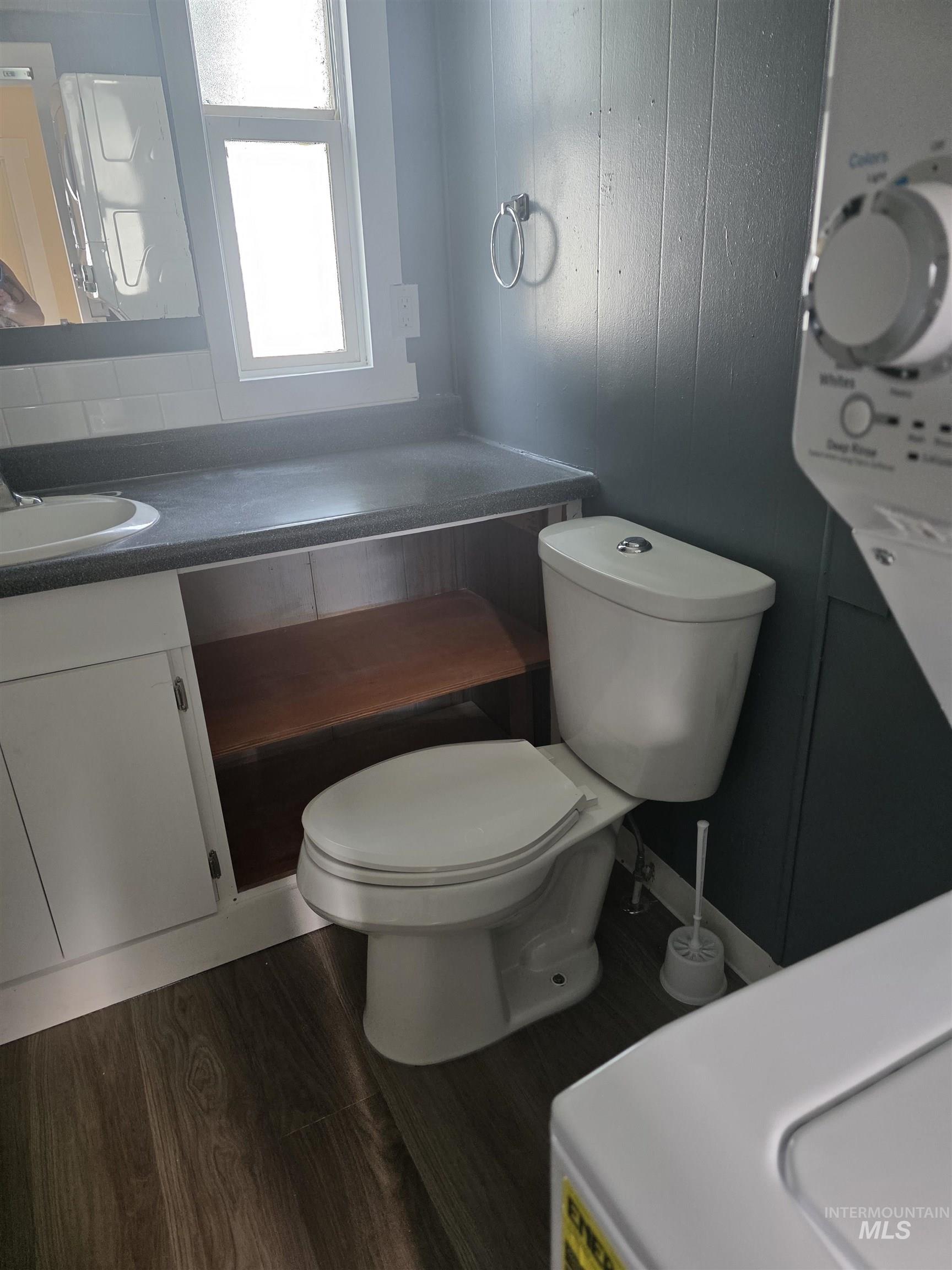 Half bathroom featuring vanity and dark wood-type flooring