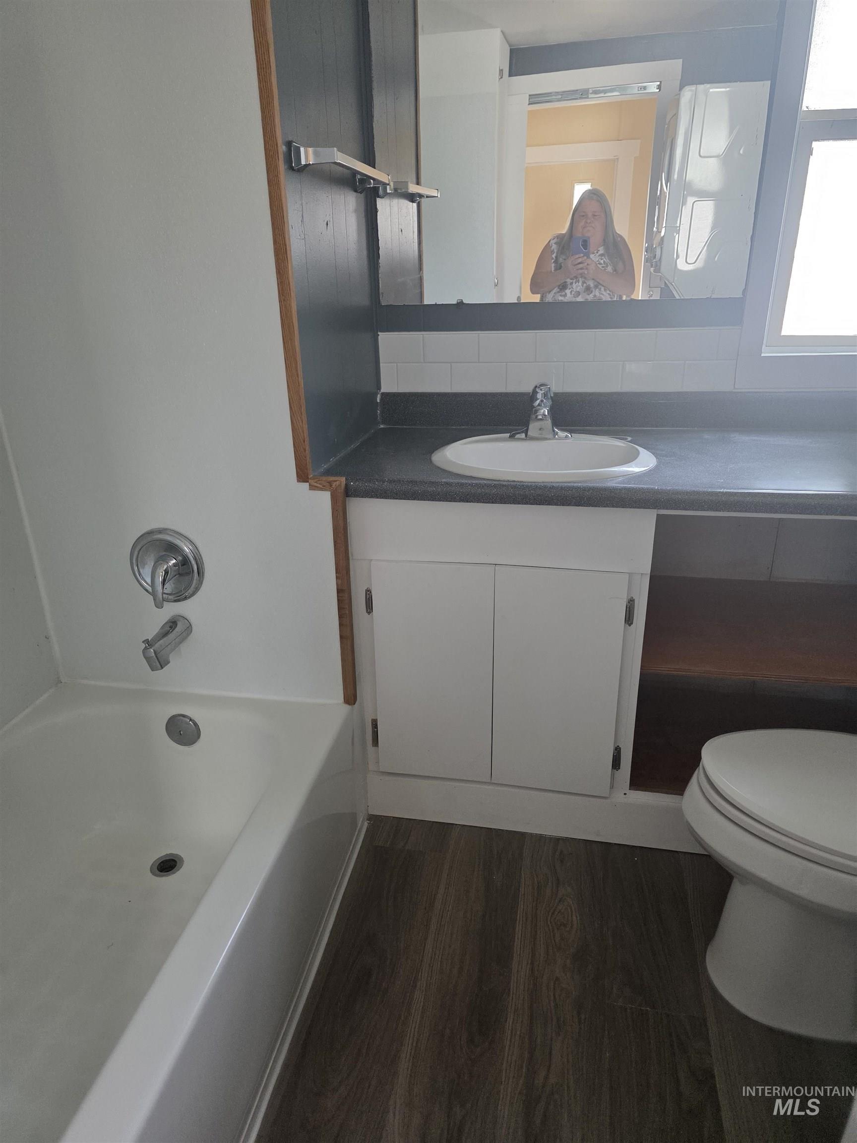 Full bathroom featuring dark wood-type flooring, vanity, and shower / washtub combination