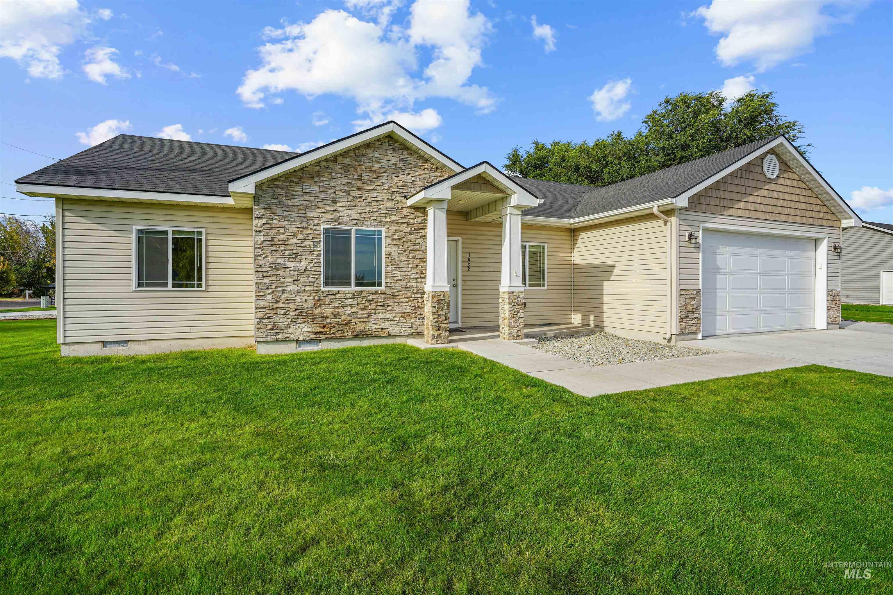 View of front of property with a front yard, an attached garage, stone siding, concrete driveway, and roof with shingles