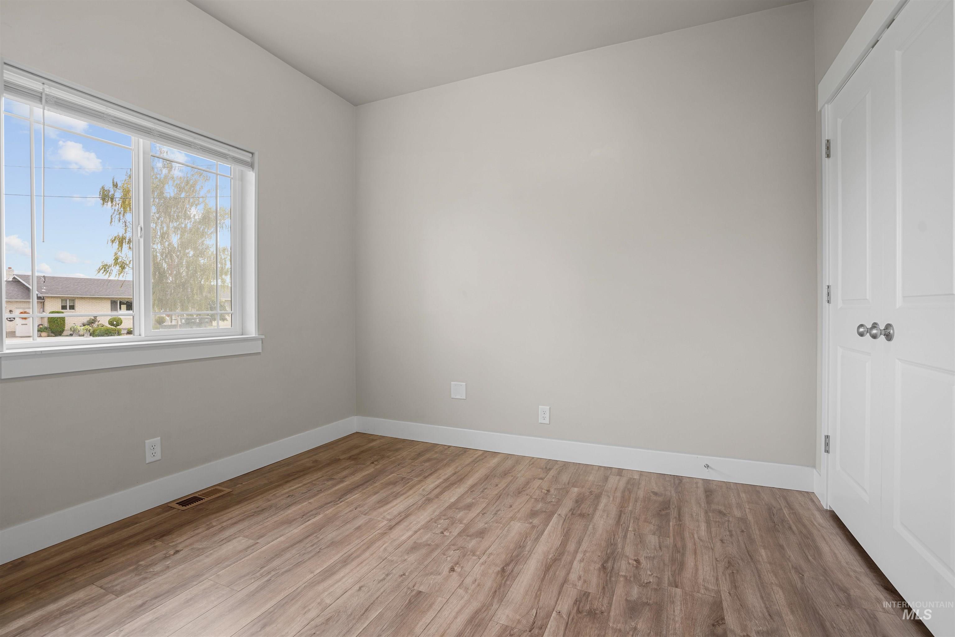 Unfurnished bedroom with light wood finished floors and baseboards