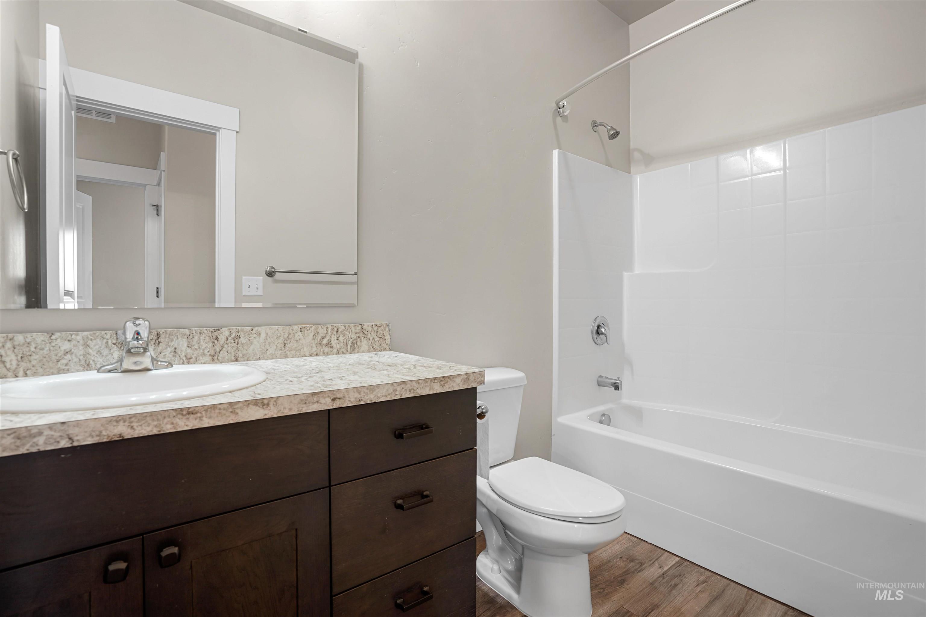Full bathroom featuring wood finished floors, vanity, and bathing tub / shower combination