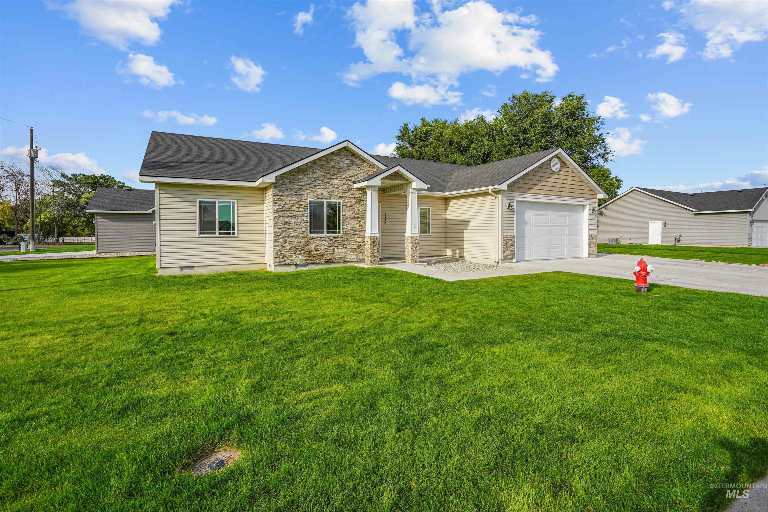 View of front facade featuring stone siding, concrete driveway, a front lawn, an attached garage, and roof with shingles