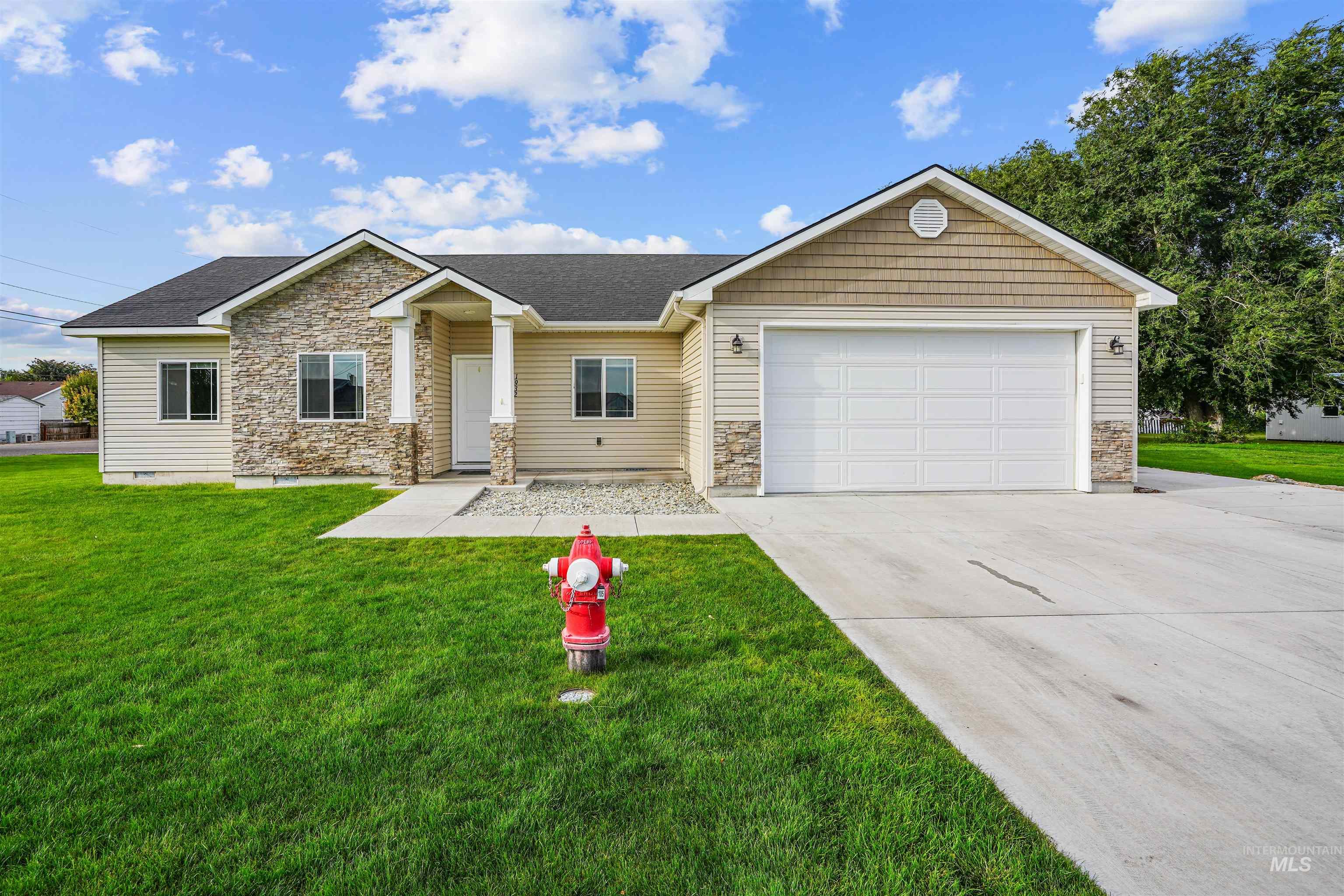 View of front of house with stone siding, a front yard, concrete driveway, and an attached garage